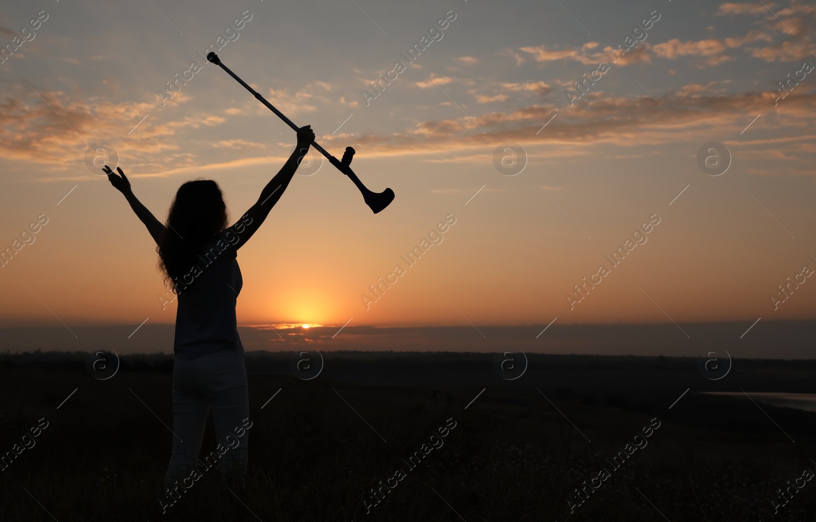 Photo of Woman holding elbow crutch outdoors at sunrise, back view. Healing miracle