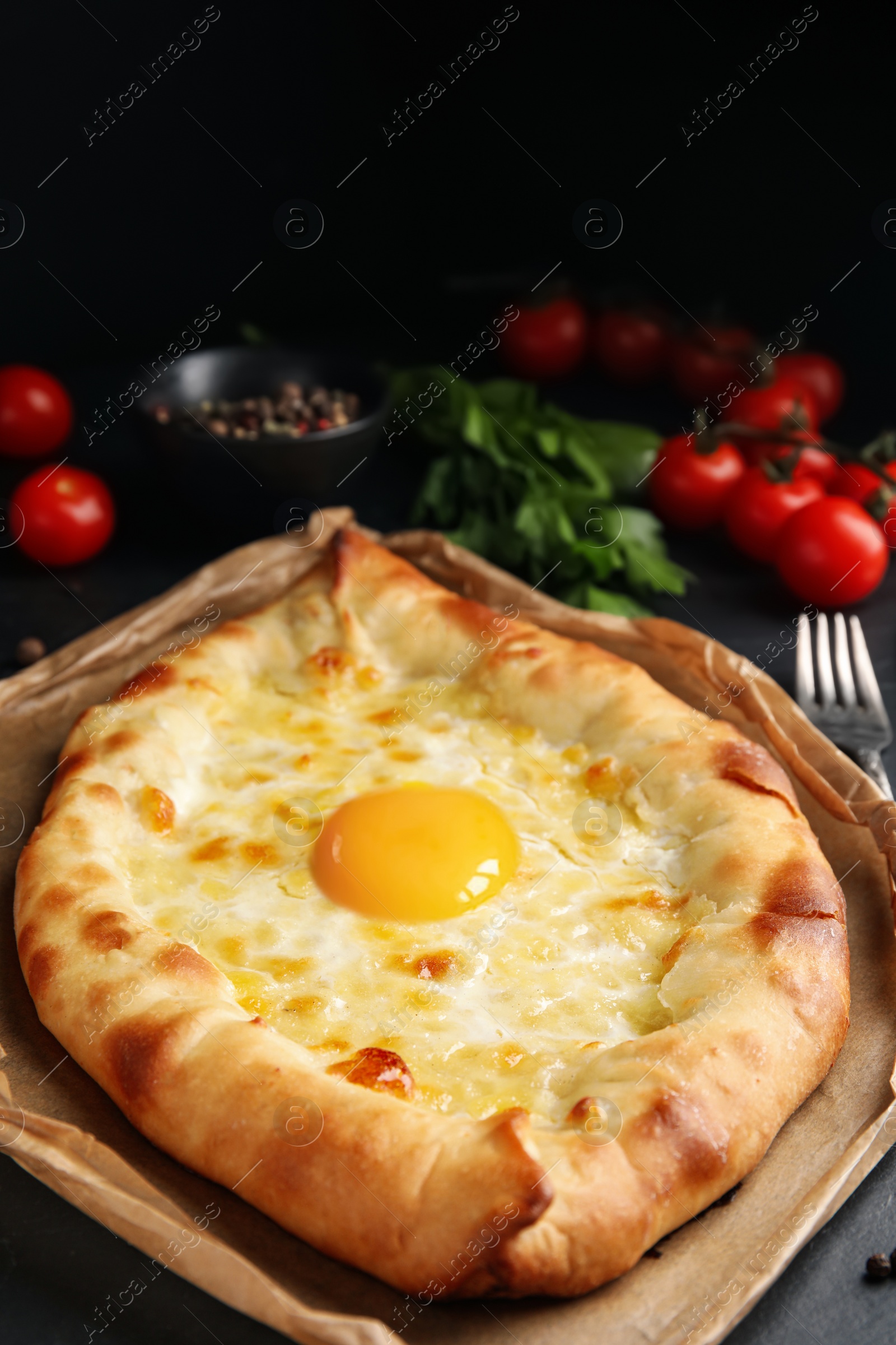 Photo of Fresh delicious Adjarian khachapuri served on black table, closeup