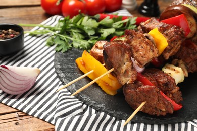Delicious shish kebabs with vegetables on wooden table, closeup