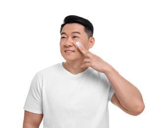 Handsome man applying cream onto his face on white background