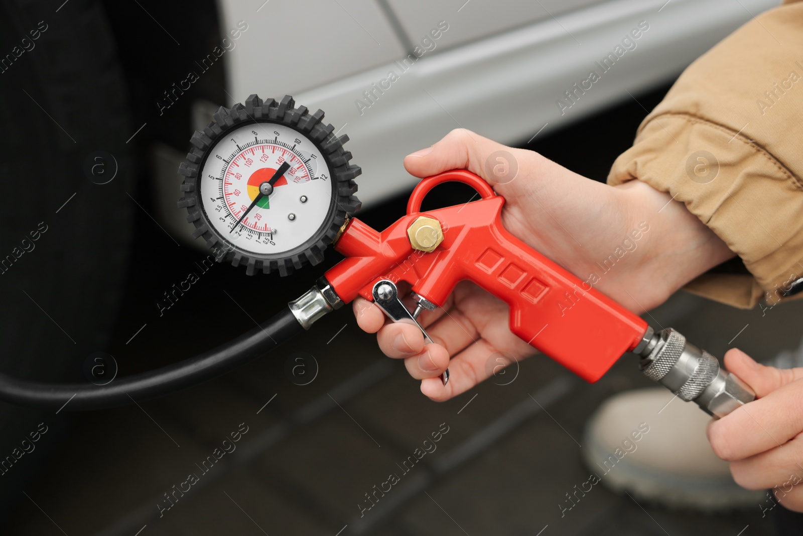 Photo of Young woman inflating tire at car service, closeup