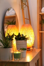 Photo of Green plants, lamp and different accessories on wooden table indoors. Interior design