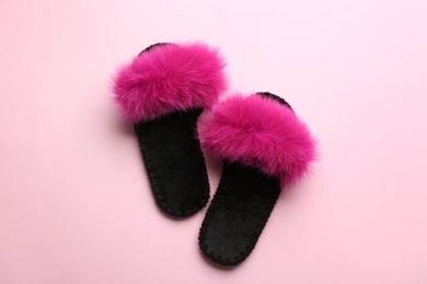 Photo of Pair of soft slippers on light pink background, flat lay