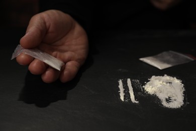Photo of Drug addiction. Man with cocaine at grey textured table, closeup