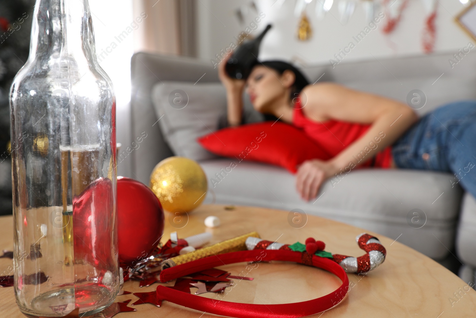 Photo of Young woman suffering from hangover  after New Year party, focus on messy table