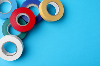 Photo of Colorful insulating tapes on light blue background, flat lay. Space for text