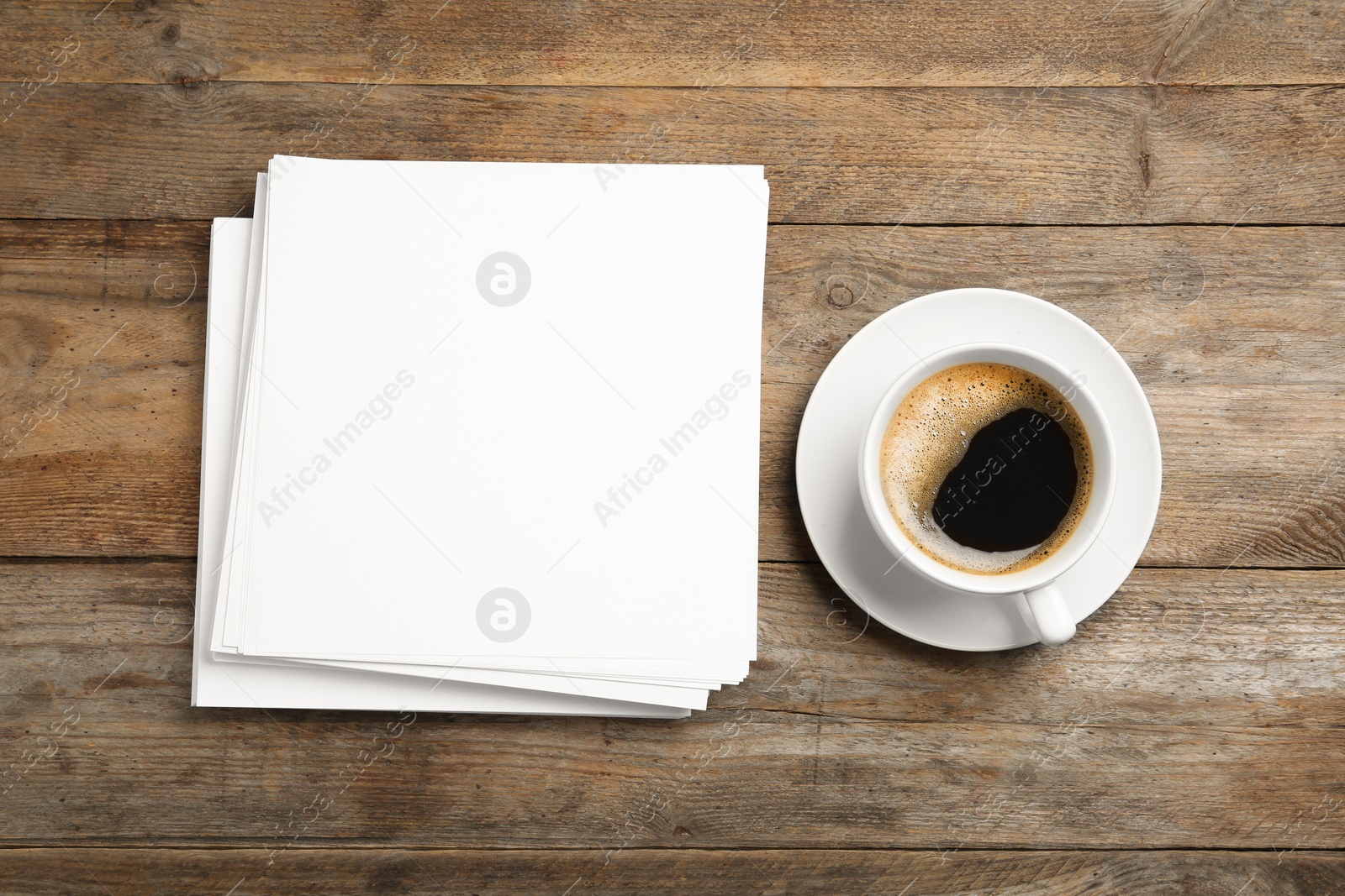 Photo of Blank paper sheets for brochure and cup of coffee on wooden background, flat lay. Mock up