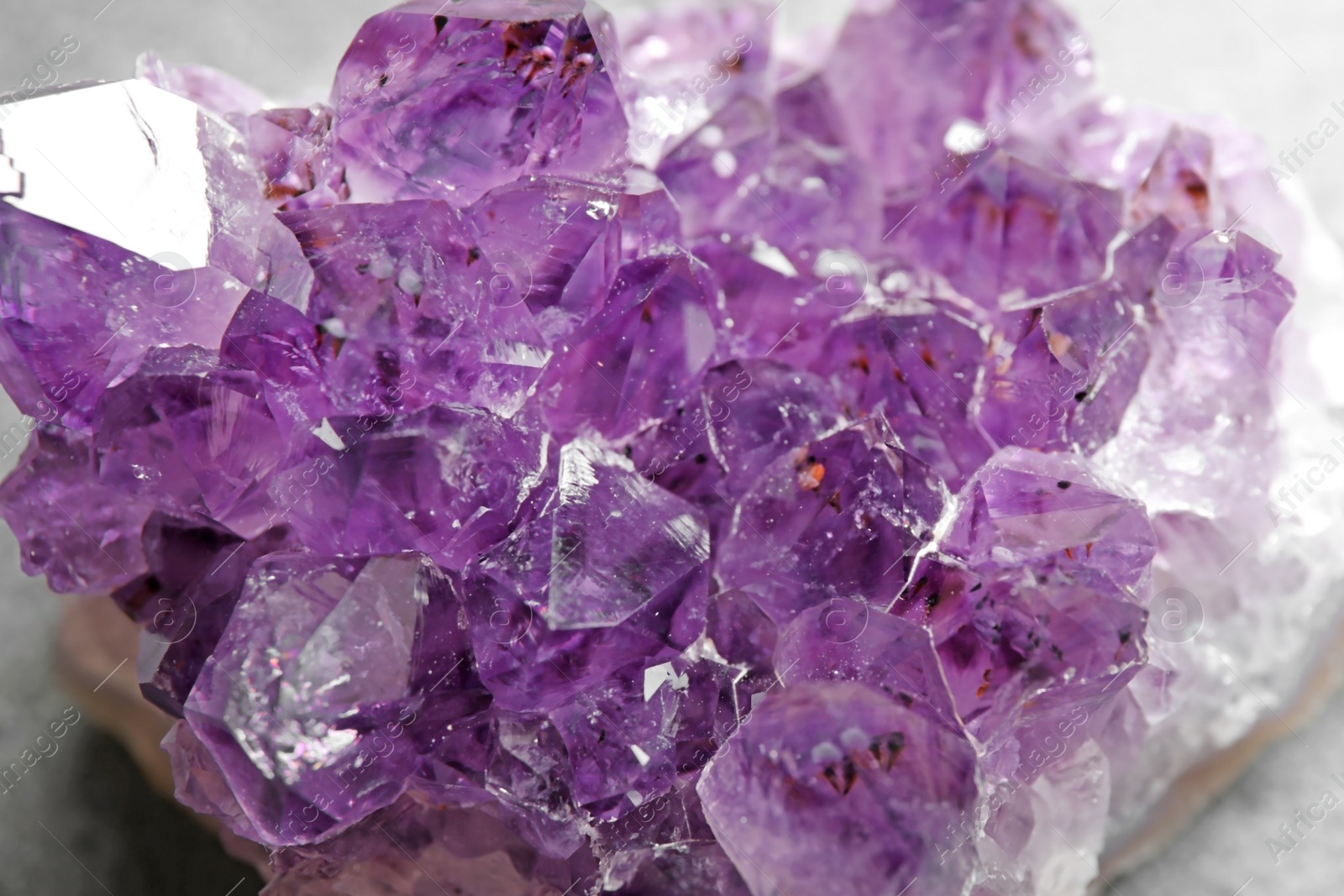 Photo of Beautiful purple amethyst gemstone on grey table, closeup