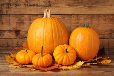 Pile of ripe pumpkins and dry leaves on wooden table