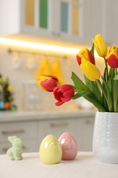 Photo of Bouquet of tulips and Easter decorations on white table indoors