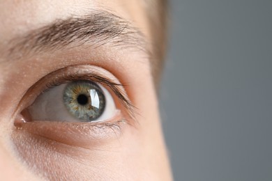 Photo of Perfect vision. Man with beautiful eyes on grey background, closeup. Space for text