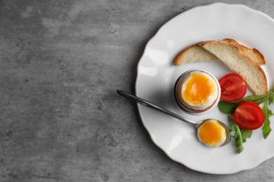 Photo of Breakfast with soft boiled egg on grey table, top view. Space for text