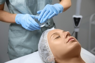 Cosmetologist applying chemical peel product on client's face in salon