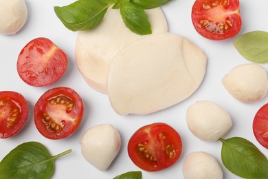Photo of Mozzarella, tomatoes and basil on white background, flat lay. Caprese salad ingredients