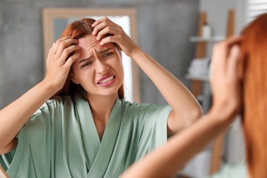 Suffering from allergy. Young woman checking her face near mirror in bathroom