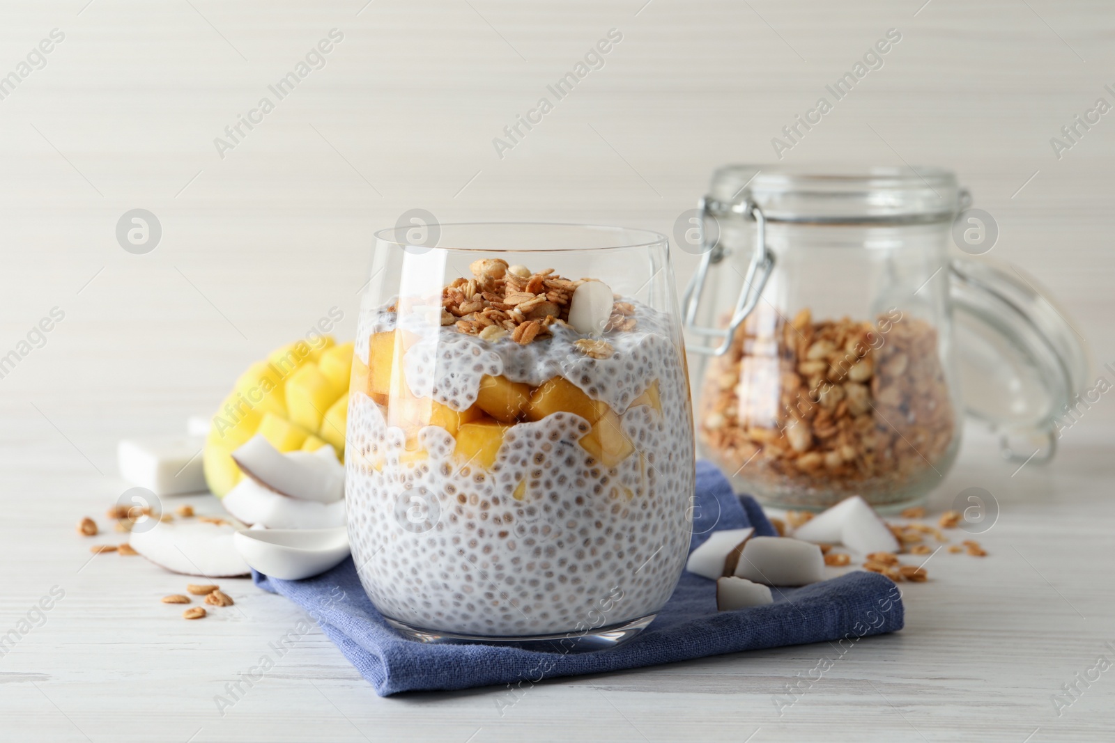 Photo of Delicious chia pudding with granola and mango on white wooden table