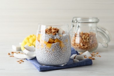 Delicious chia pudding with granola and mango on white wooden table