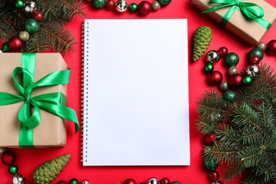 Flat lay composition with empty notebook and Christmas decorations on red background, space for text. Writing letter to Santa Claus