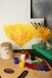 Photo of Painting of chrysanthemum, flower, colorful paints, brushes and artist`s palette on wooden table
