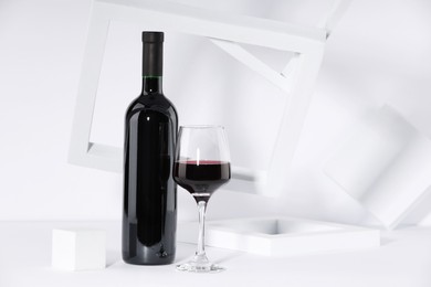 Photo of Stylish presentation of delicious red wine in bottle and glass on white background. Space for text