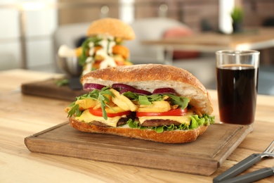 Wooden serving plate with yummy sandwich on table in cafe