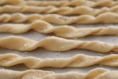Homemade breadsticks with sesame on baking sheet, closeup. Cooking traditional grissini