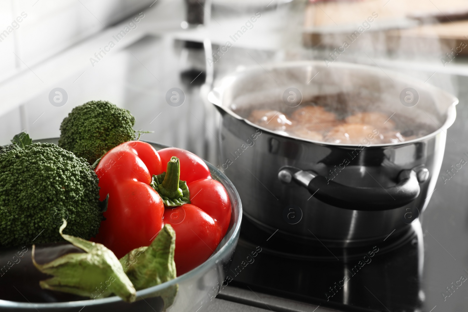 Photo of Bowl of vegetables near pot with boiling water and eggs on stove