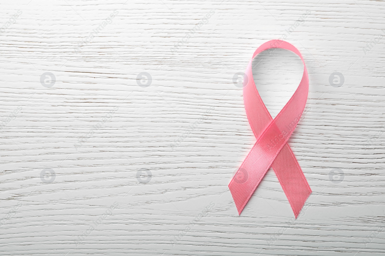 Photo of Pink ribbon on wooden background, top view with space for text. Breast cancer awareness concept