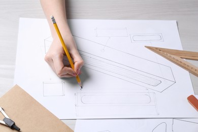 Woman creating packaging design at light wooden table, above view