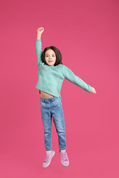 Cute little girl jumping on pink background