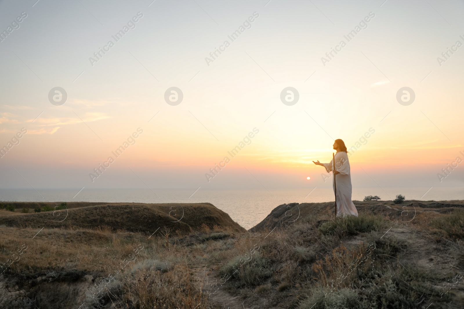 Photo of Jesus Christ on hills at sunset. Space for text