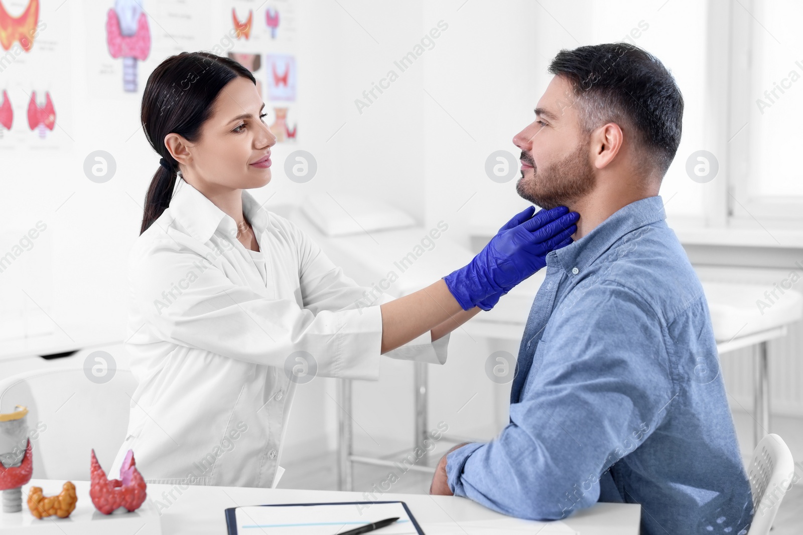 Photo of Endocrinologist examining thyroid gland of patient at table in hospital