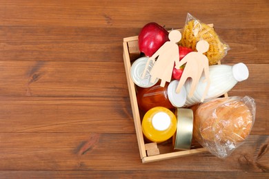 Humanitarian aid for elderly people. Different donation food products and figures of senior couple on wooden table, top view. Space for text