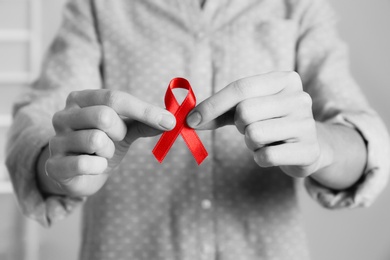 Image of World AIDS disease day. Woman holding red awareness ribbon, closeup 