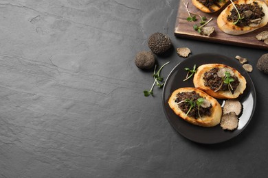 Photo of Delicious bruschettas with truffle sauce and microgreens on black table, flat lay. Space for text