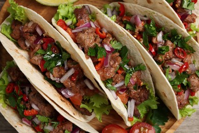 Photo of Delicious tacos with meat and vegetables on table, top view