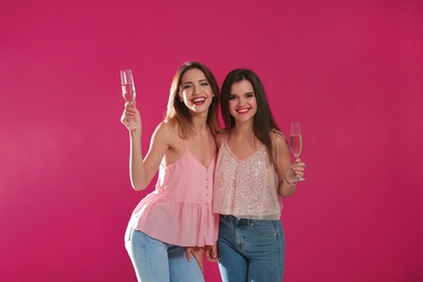 Portrait of happy friends with champagne in glasses on color background