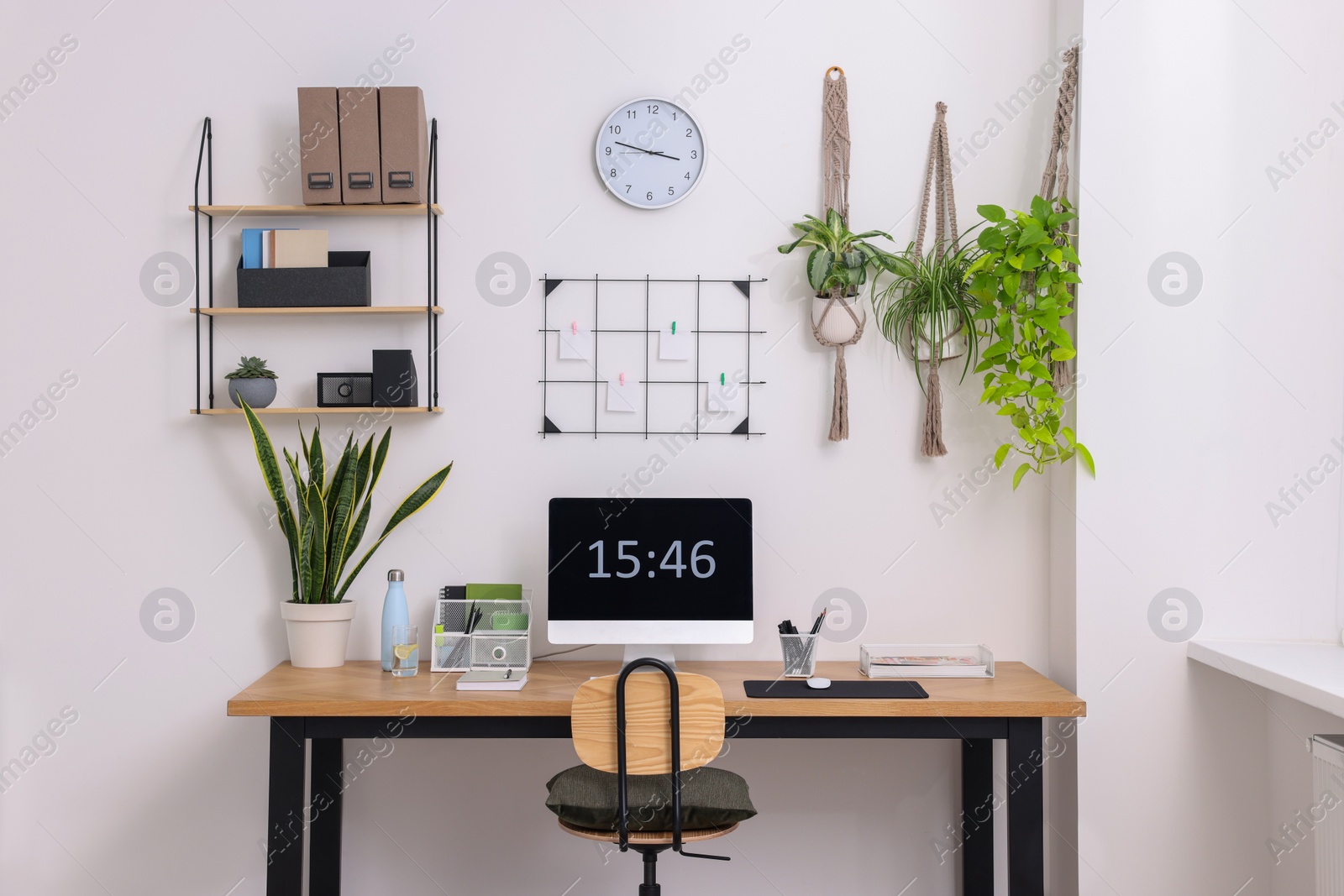 Photo of Cozy workplace with computer, modern furniture and houseplants at home