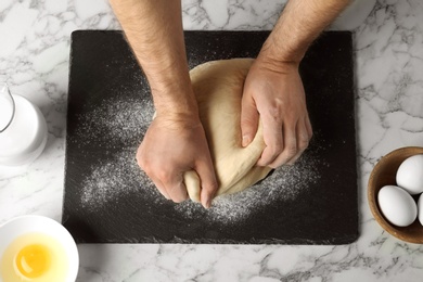 Photo of Male baker preparing bread dough at kitchen table, top view