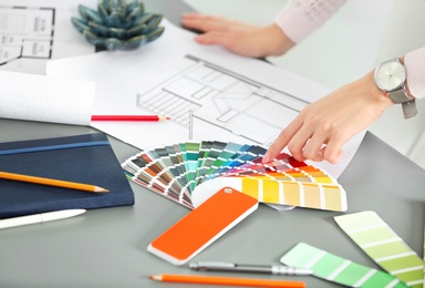 Photo of Female designer working with color palette samples at table