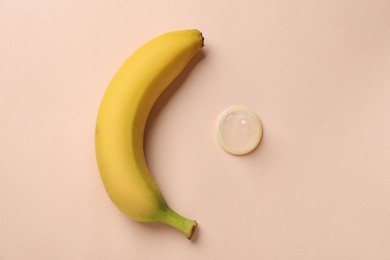 Banana and condom on beige background, flat lay. Safe sex concept