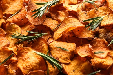 Photo of Sweet potato chips with rosemary as background, closeup