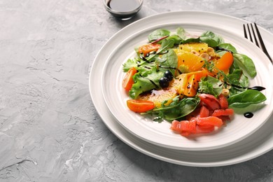 Delicious salad with salmon on gray textured table, space for text