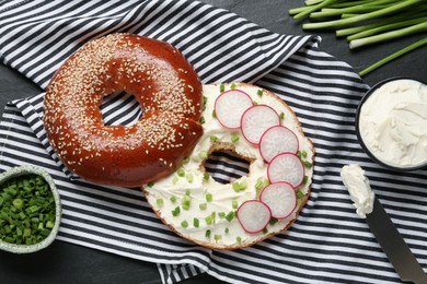 Photo of Delicious bagel with cream cheese, green onion and radish on table, flat lay