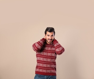 Portrait of happy man in Christmas sweater on beige background