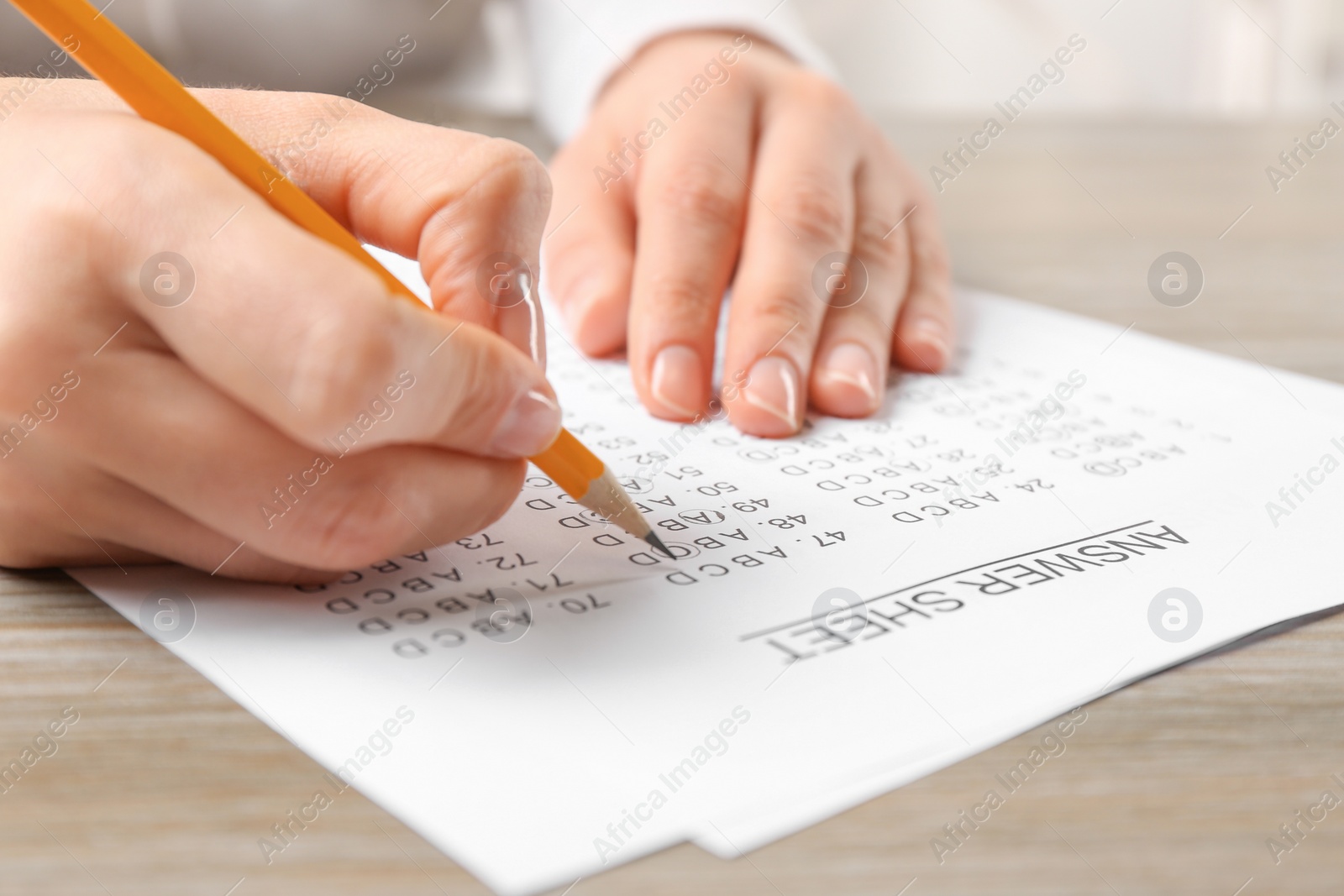 Photo of Student filling answer sheet at table, closeup