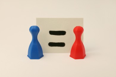 Photo of Gender equality concept. Game pieces and card with equal sign on white background.