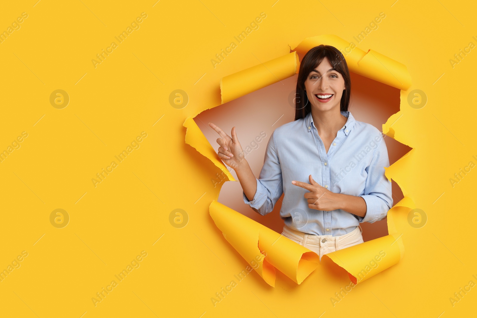 Photo of Special promotion. Woman pointing at something through hole in orange paper. Space for text