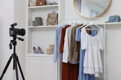 Photo of Fashion blogger's workplace. Shoes, clothes, camera and stylish furniture indoors