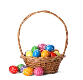 Photo of Decorated Easter eggs in wicker basket on white background